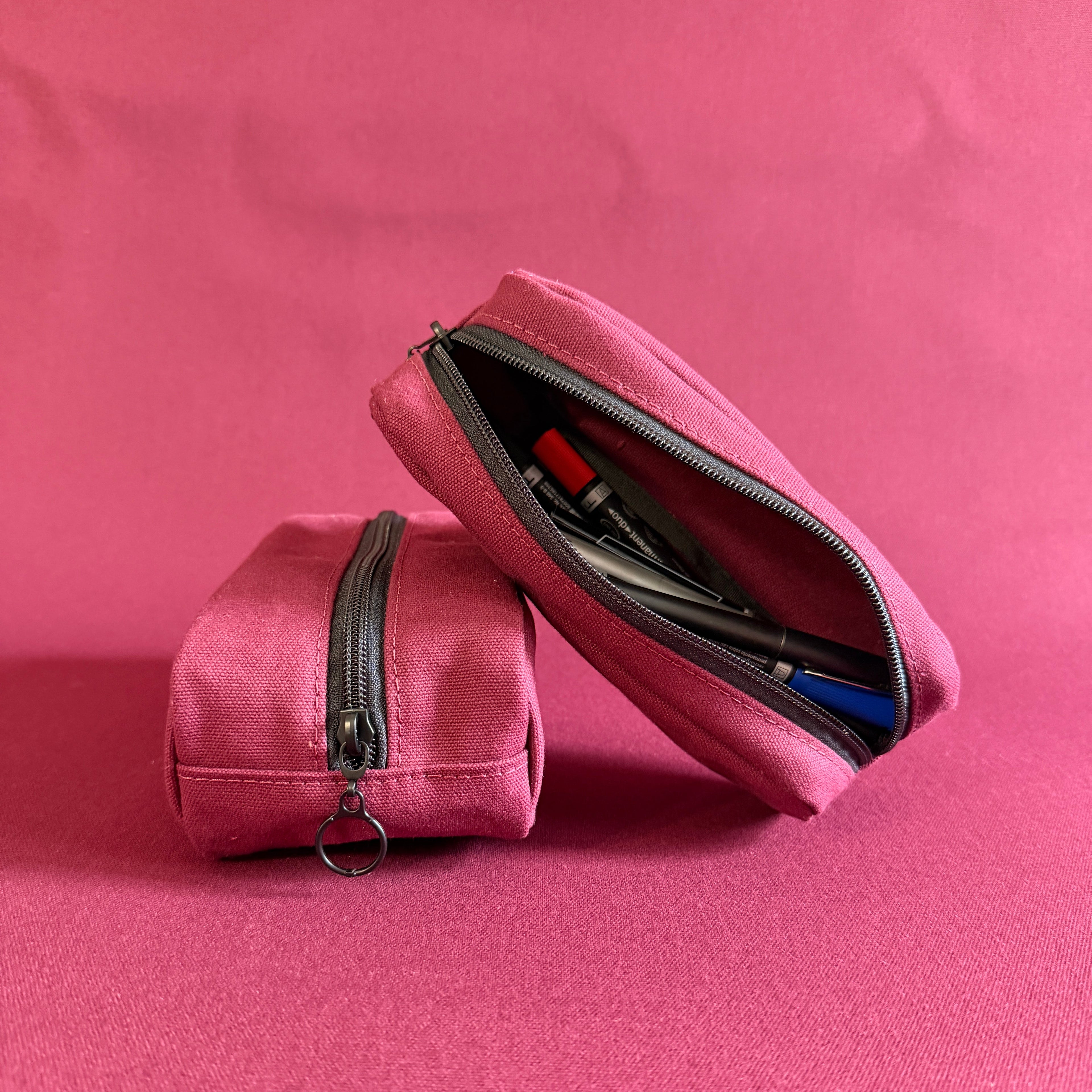 Two deep red pen pouches on a matching backdrop
