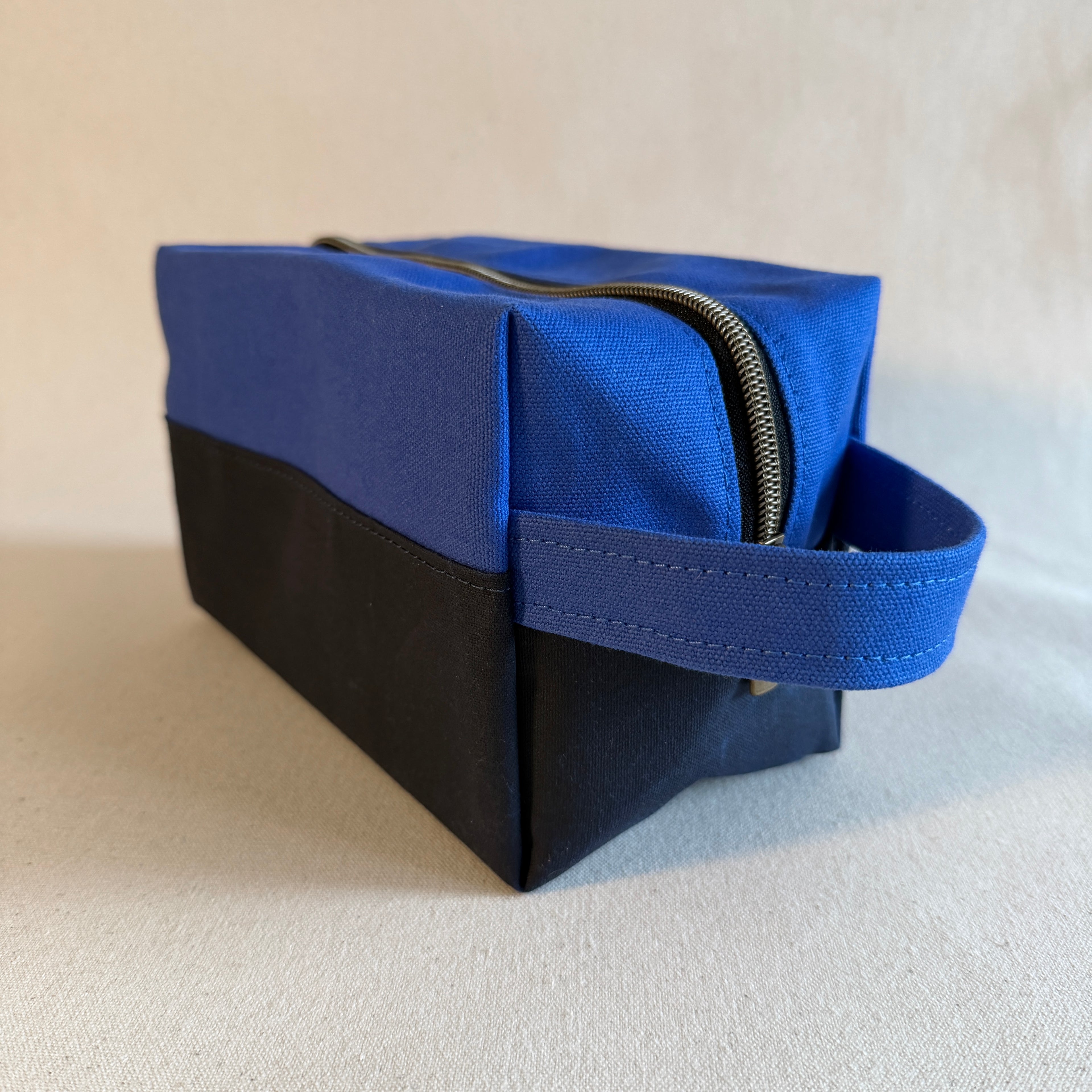 Blue and navy toiletry bag on a light beige background