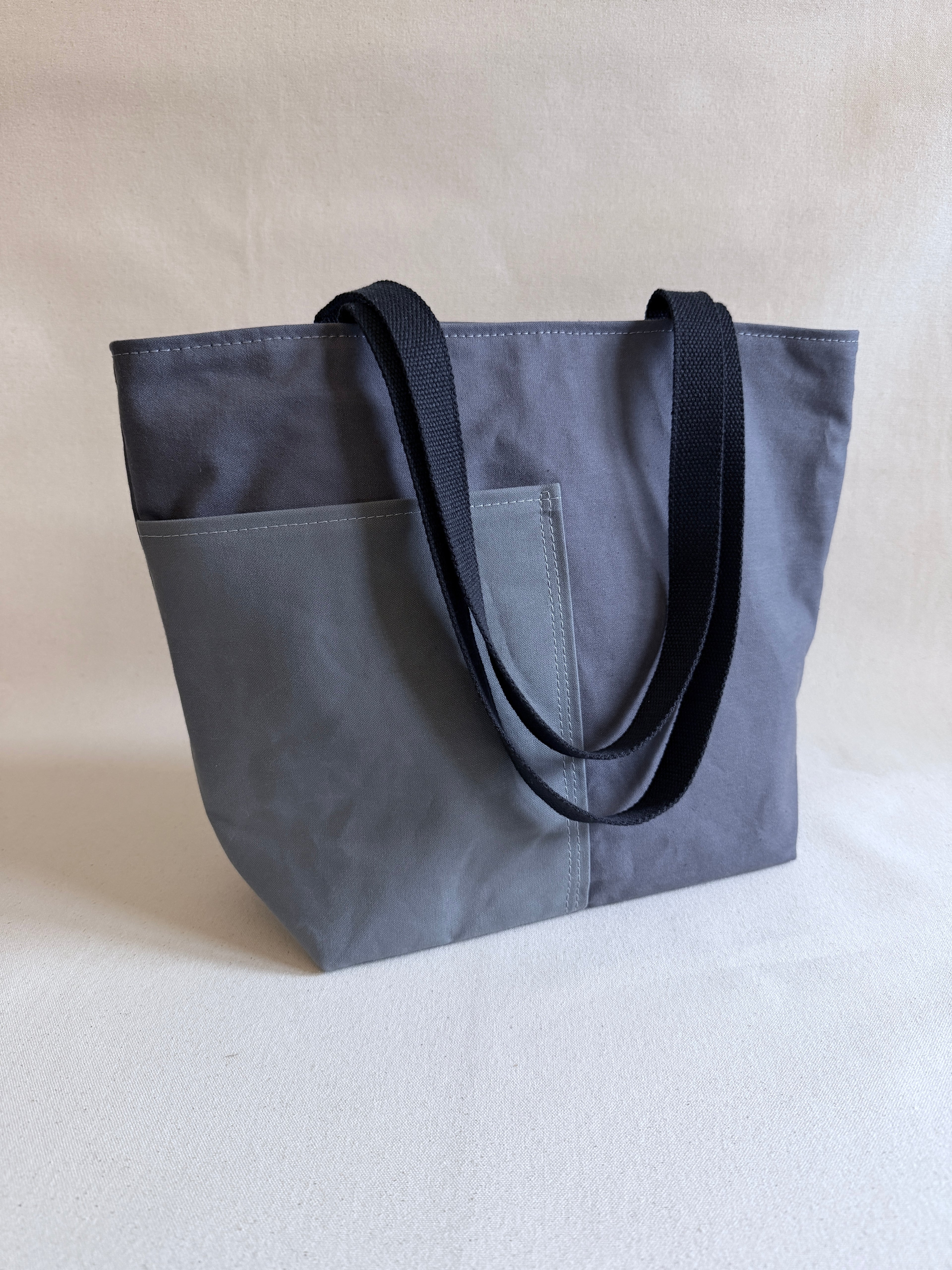 Gray tote bag with two black handles on a neutral background