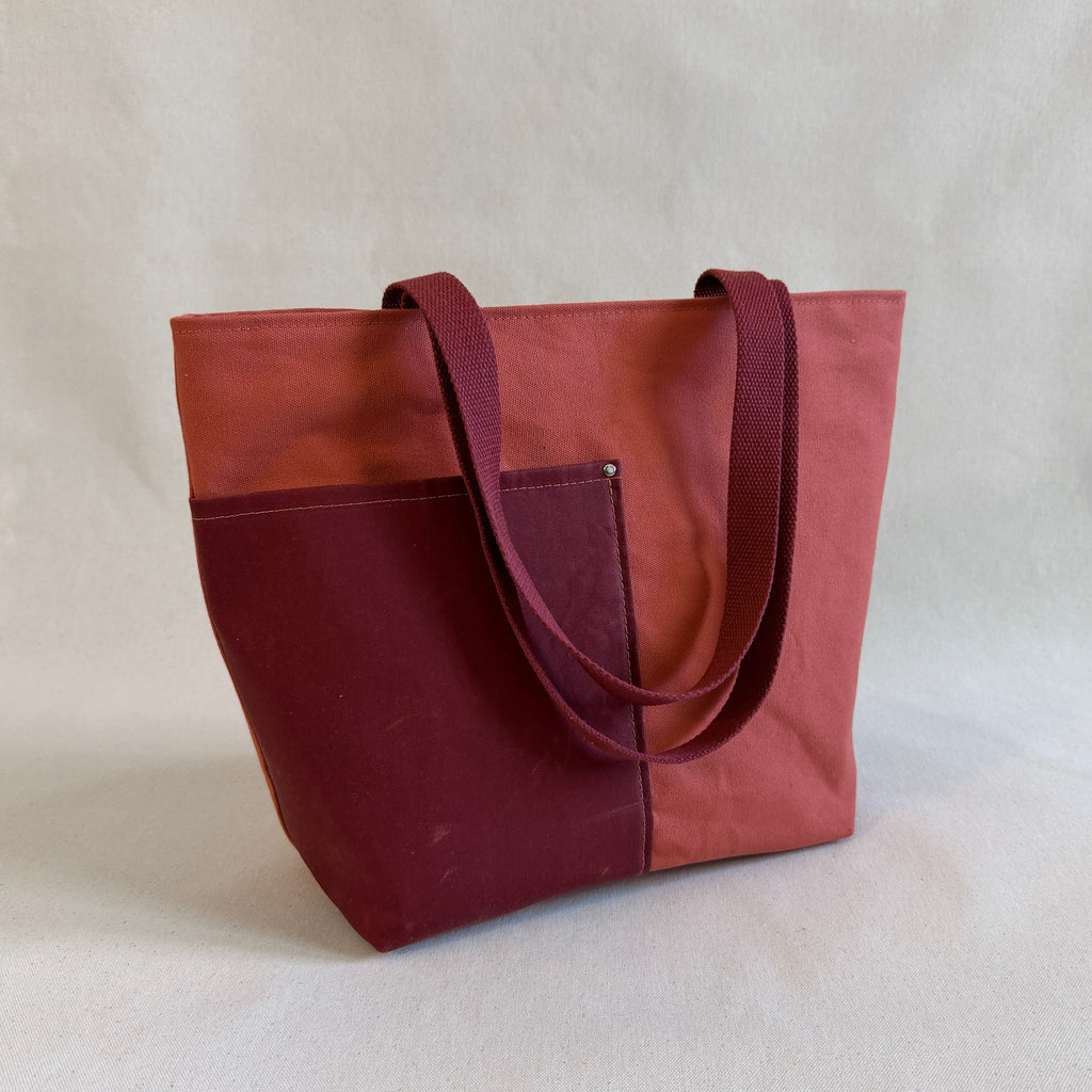 Two-toned terra cotta and dark reddish-orange tote bag on a light beige background