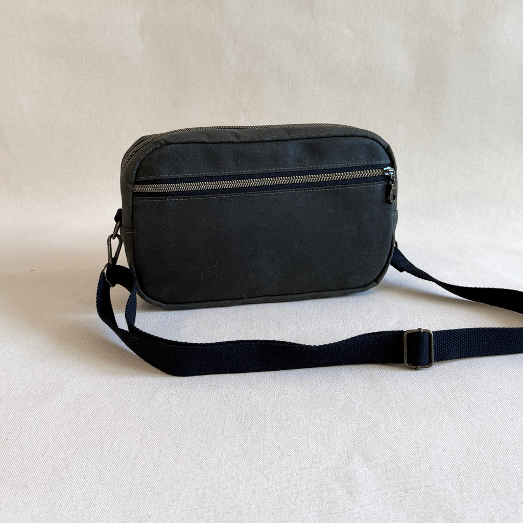 Dark olive green crossbody bag on a light beige background